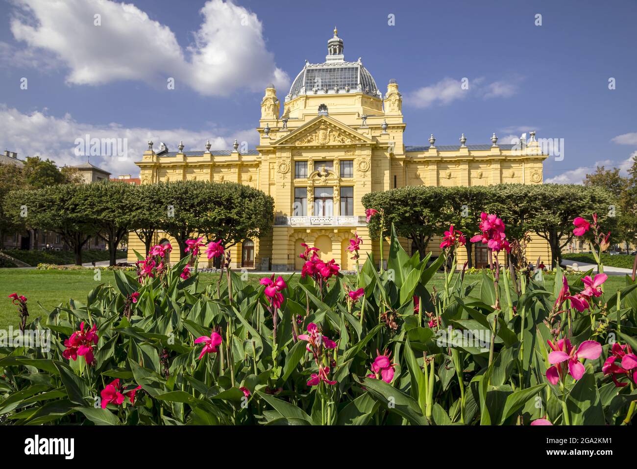 Farbenprächtiges Blumenbeet vor der gelben Steinfassade des Art Pavilion in Zagreb auf dem Lenuci Hufeisen, Unterstadt am König-Tomislav-Platz Stockfoto