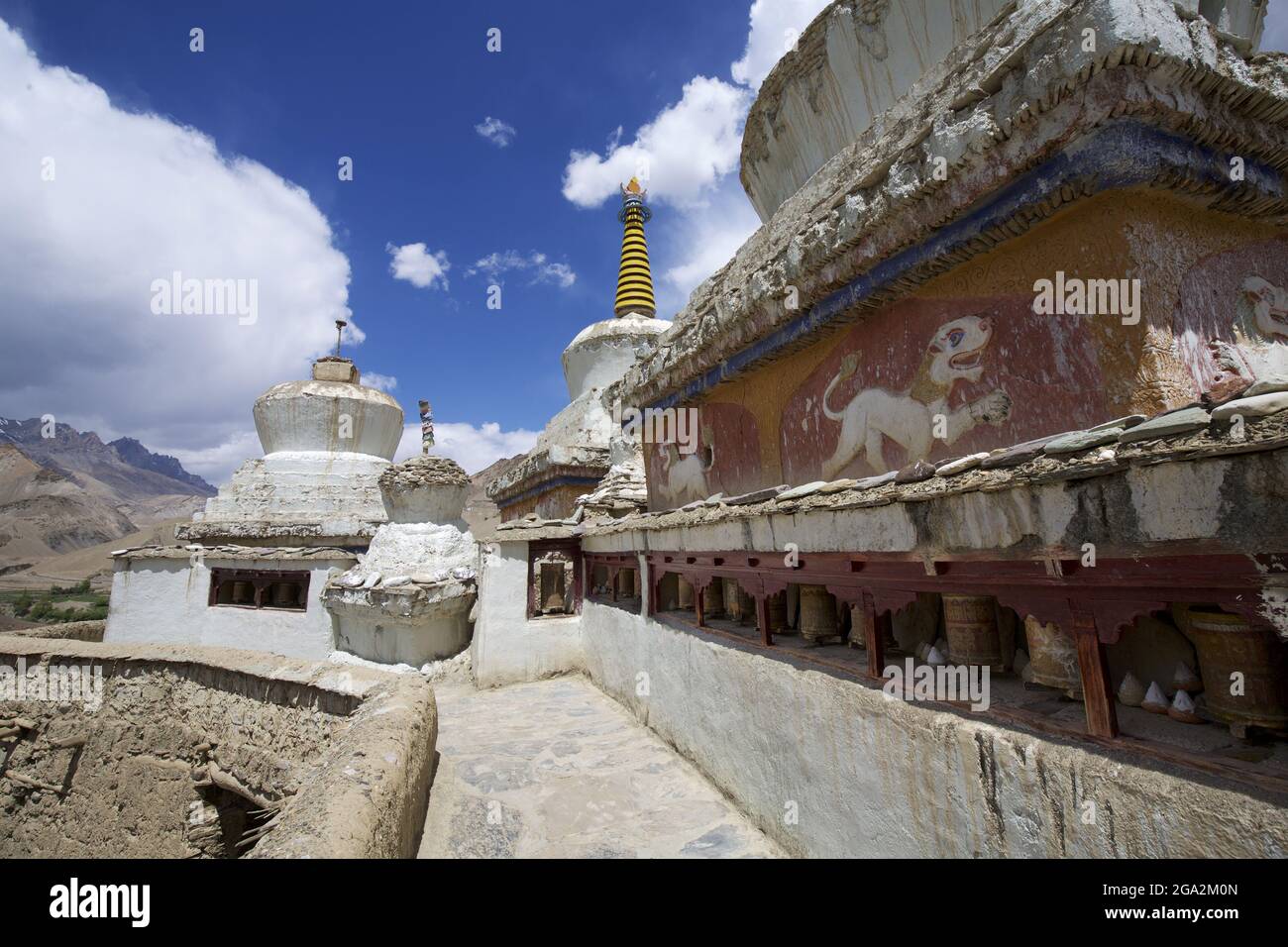 Nahaufnahme eines Betonweges durch die weißgetünchten buddhistischen Stupas (in der tibetischen Kultur als Chöre bekannt) und Gebetsräder an den Lamayuru Monas... Stockfoto