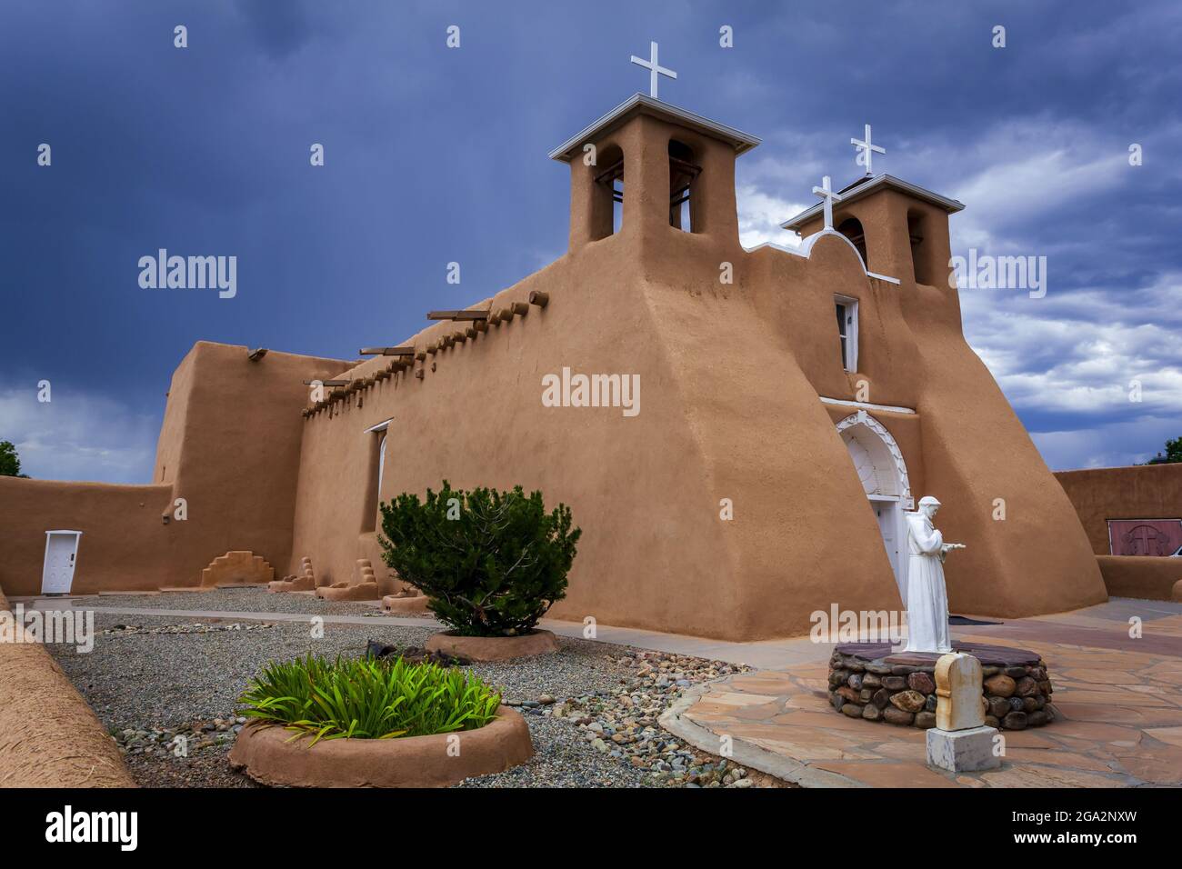 Seitenansicht der historischen Kirche San Francisco de Asis mit einer Statue von San Francisco of Asis im begrünten Innenhof, der sich auf dem Hauptplatz... Stockfoto