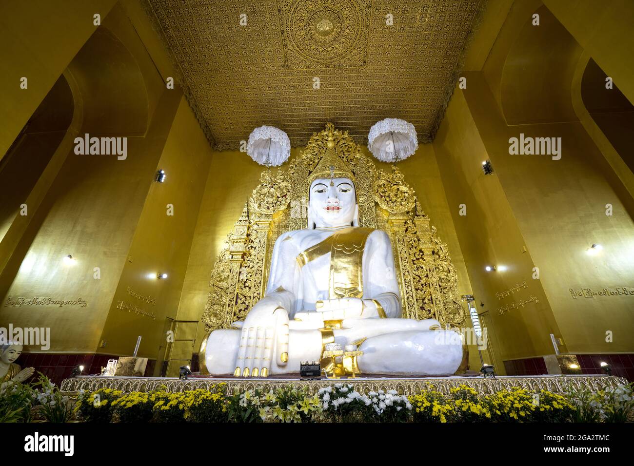 Das Innere des Mahagandhayon Klosters mit einer weißen Marmorstatue eines sitzenden Buddha mit vergoldeten Accessoires und umgeben von goldenen Wänden Stockfoto