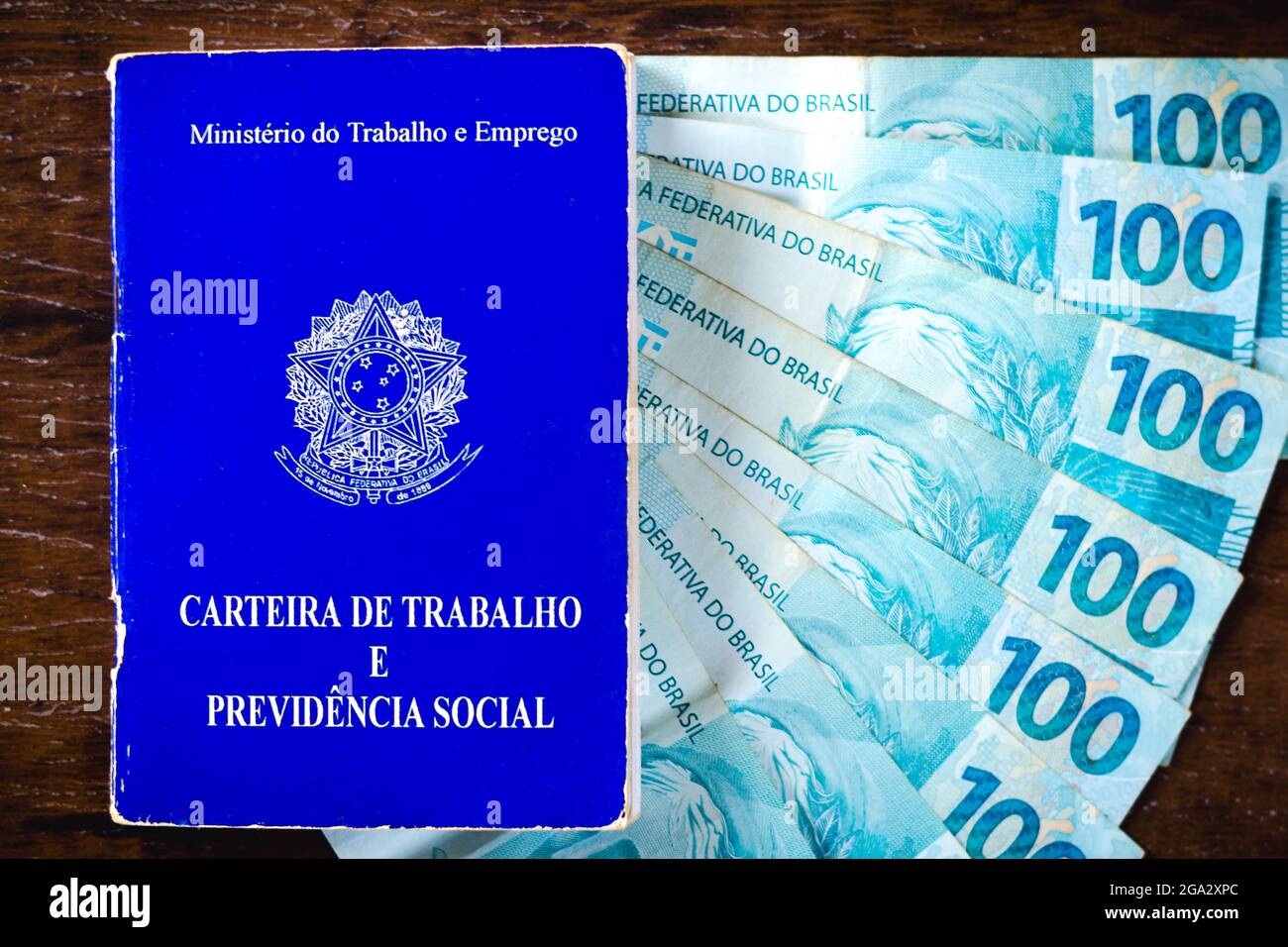 In dieser Abbildung zeigt die Arbeits- und Sozialversicherungskarte Brasiliens, die mit hundert Reals-Rechnungen ausgestellt ist.Es ist das Dokument, das den Zugang zu den Rechten des brasilianischen Arbeiters garantiert. Stockfoto