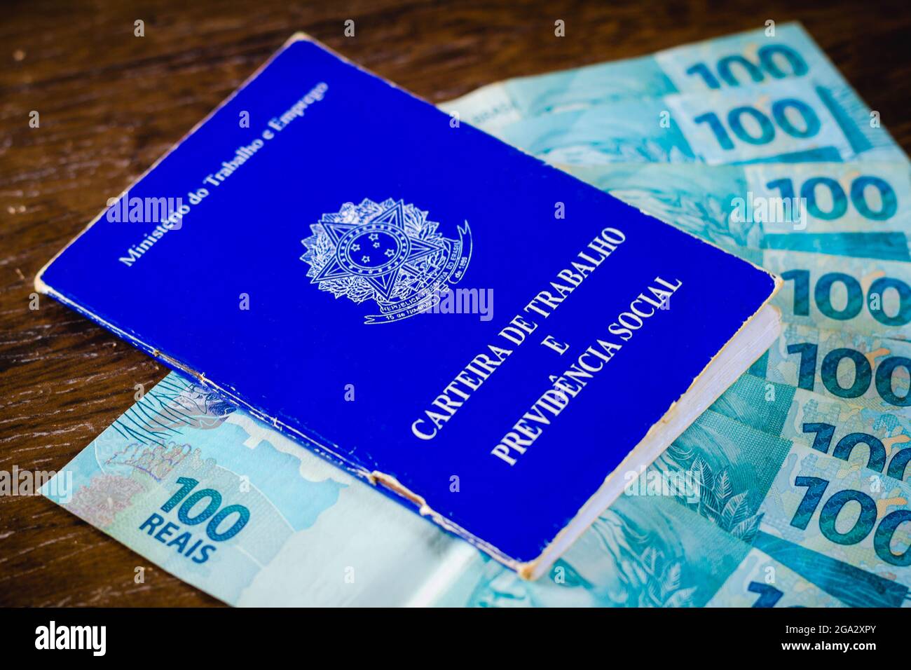 In dieser Abbildung zeigt die Arbeits- und Sozialversicherungskarte Brasiliens, die mit hundert Reals-Rechnungen ausgestellt ist.Es ist das Dokument, das den Zugang zu den Rechten des brasilianischen Arbeiters garantiert. Stockfoto
