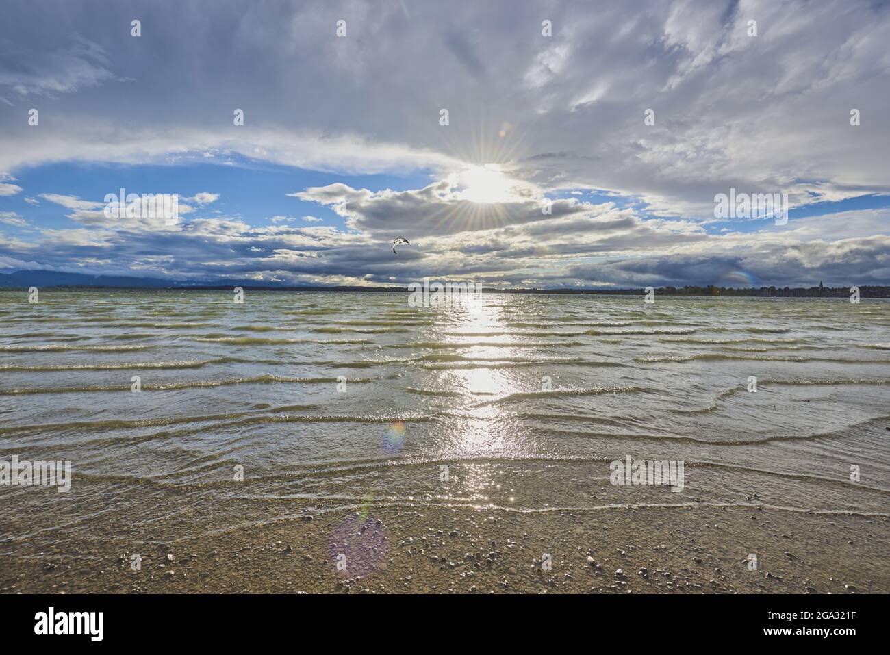 Chiemsee, mit hellem Sonnenlicht, das auf der Wasseroberfläche bis zum Ufer reflektiert wird; Bayern, Deutschland Stockfoto