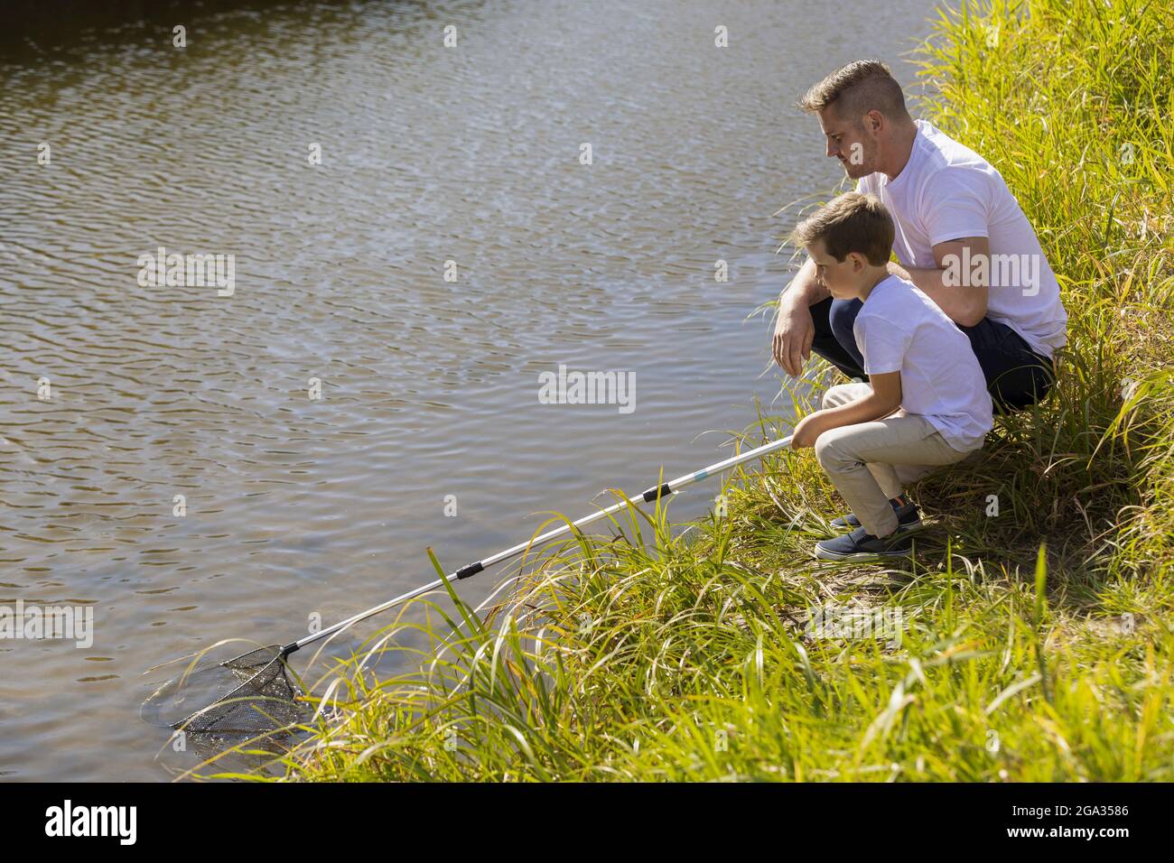 Vater und Sohn fangen in der Herbstsaison in einem Bach in einem Stadtpark Ungeziefer; Edmonton, Alberta, Kanada Stockfoto