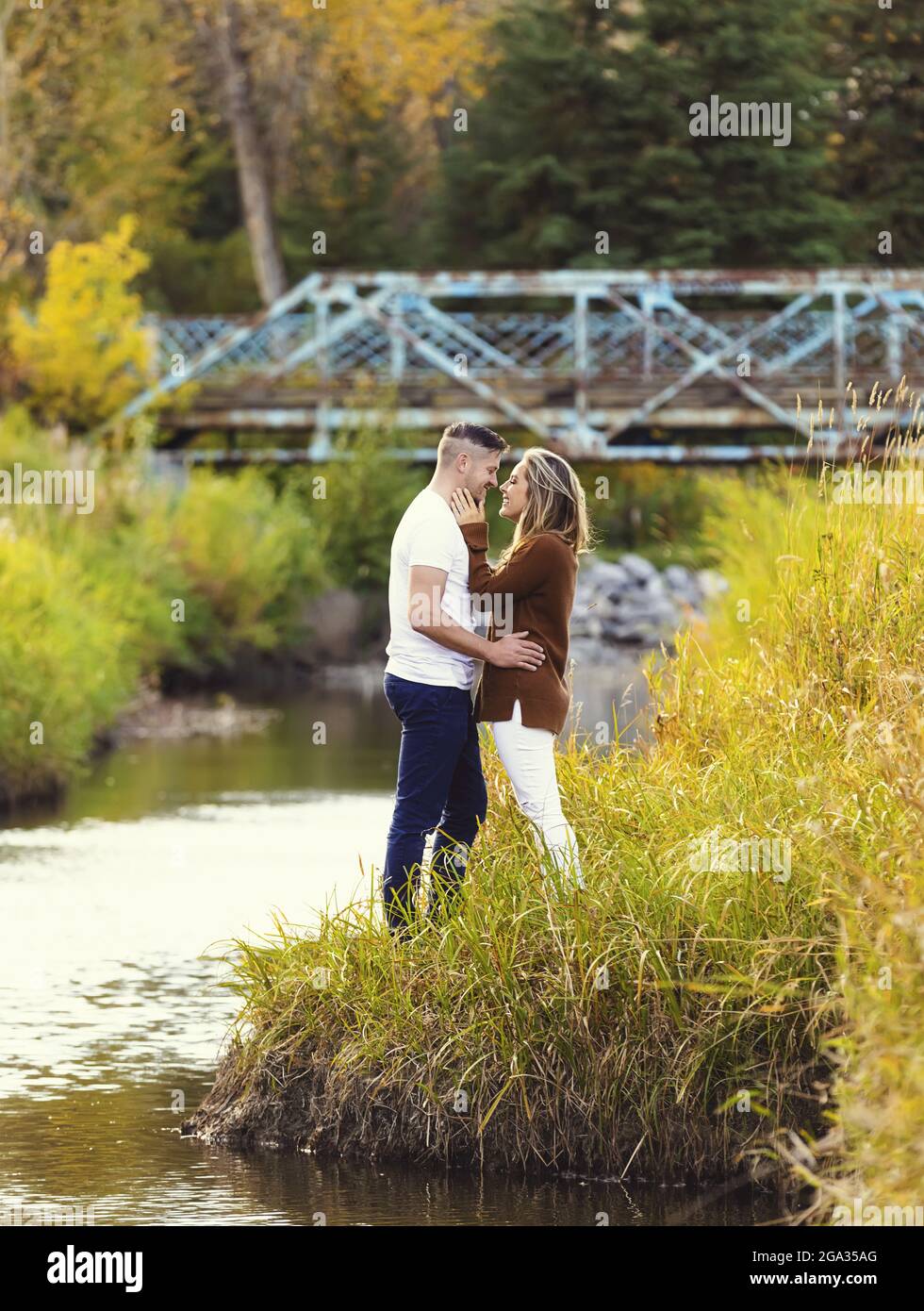 Ehemann und Ehefrau verbringen gemeinsam eine gute Zeit im Freien in der Nähe eines Baches in einem Stadtpark; Edmonton, Alberta, Kanada Stockfoto