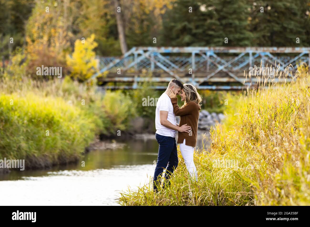 Ehemann und Ehefrau verbringen gemeinsam eine gute Zeit im Freien in der Nähe eines Baches in einem Stadtpark; Edmonton, Alberta, Kanada Stockfoto