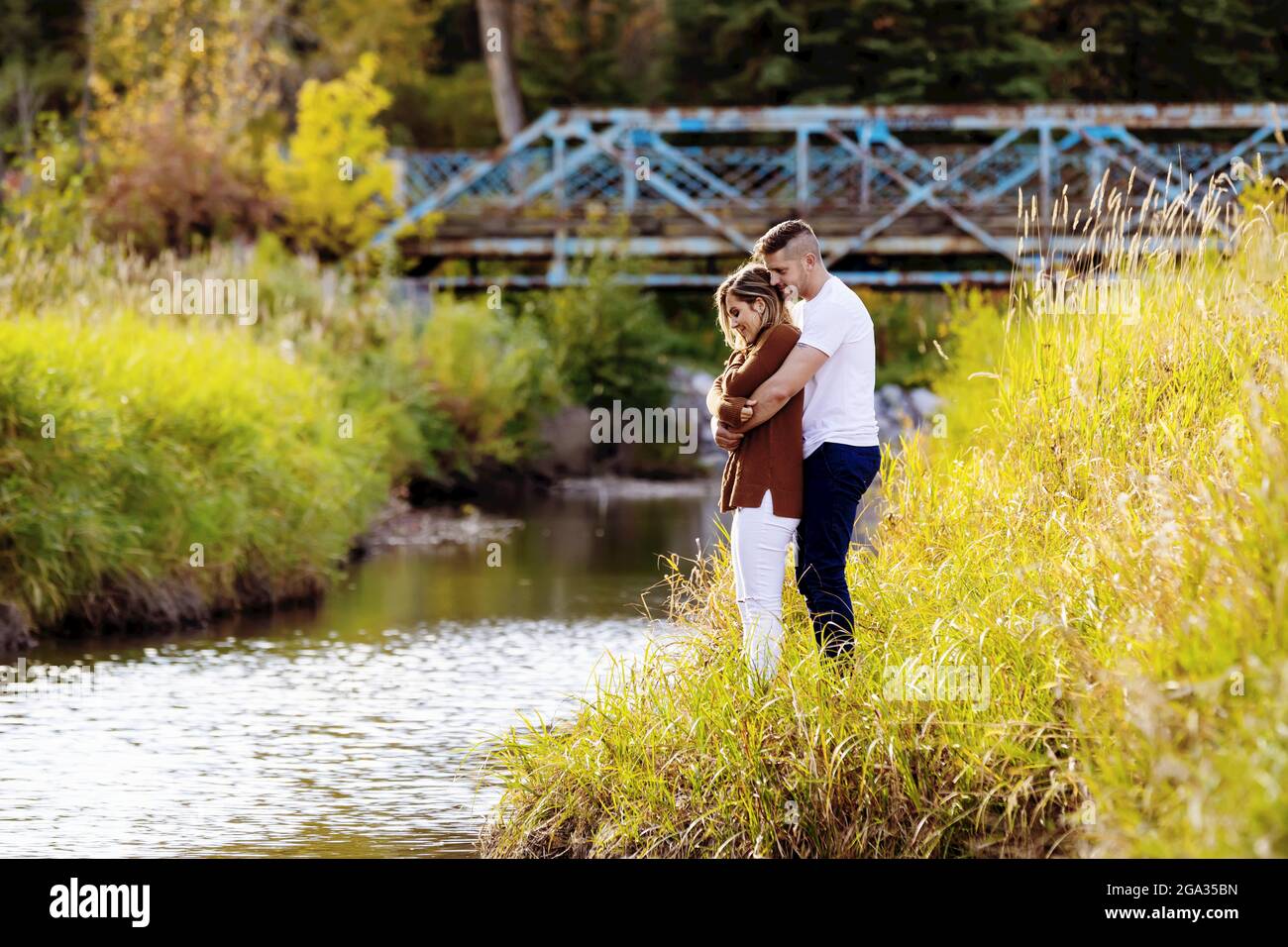 Ehemann und Ehefrau verbringen gemeinsam eine gute Zeit im Freien in der Nähe eines Baches in einem Stadtpark; Edmonton, Alberta, Kanada Stockfoto