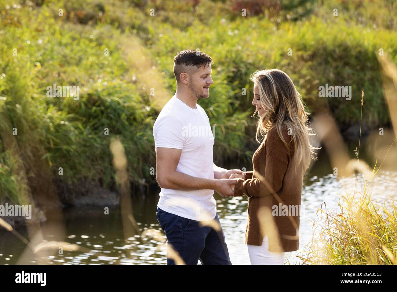 Ehemann und Ehefrau verbringen gemeinsam eine gute Zeit im Freien in der Nähe eines Baches in einem Stadtpark; Edmonton, Alberta, Kanada Stockfoto