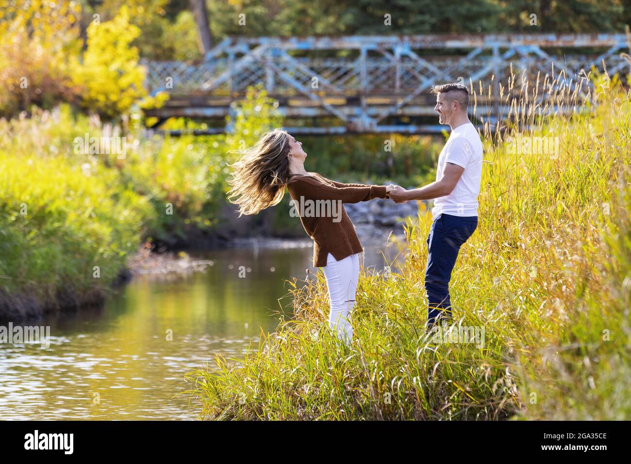 Ehemann und Ehefrau verbringen gemeinsam eine gute Zeit im Freien in der Nähe eines Baches in einem Stadtpark; Edmonton, Alberta, Kanada Stockfoto