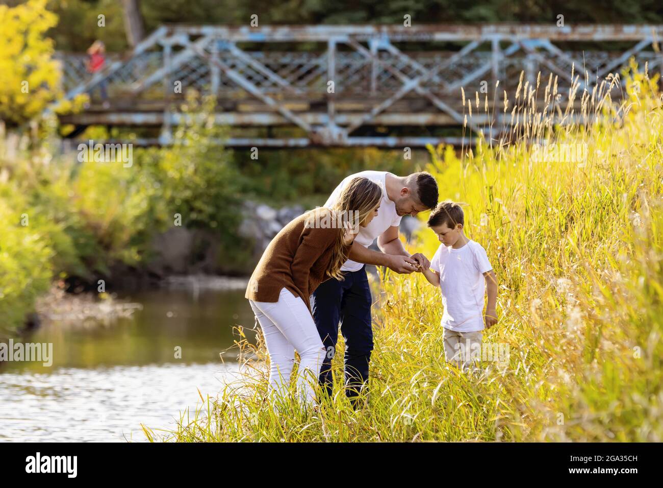Ein Vater, eine Mutter und ihr Sohn verbringen während der Herbstsaison in Edmonton, Alberta, Kanada, eine gute Zeit im Freien entlang eines Baches in einem Stadtpark Stockfoto