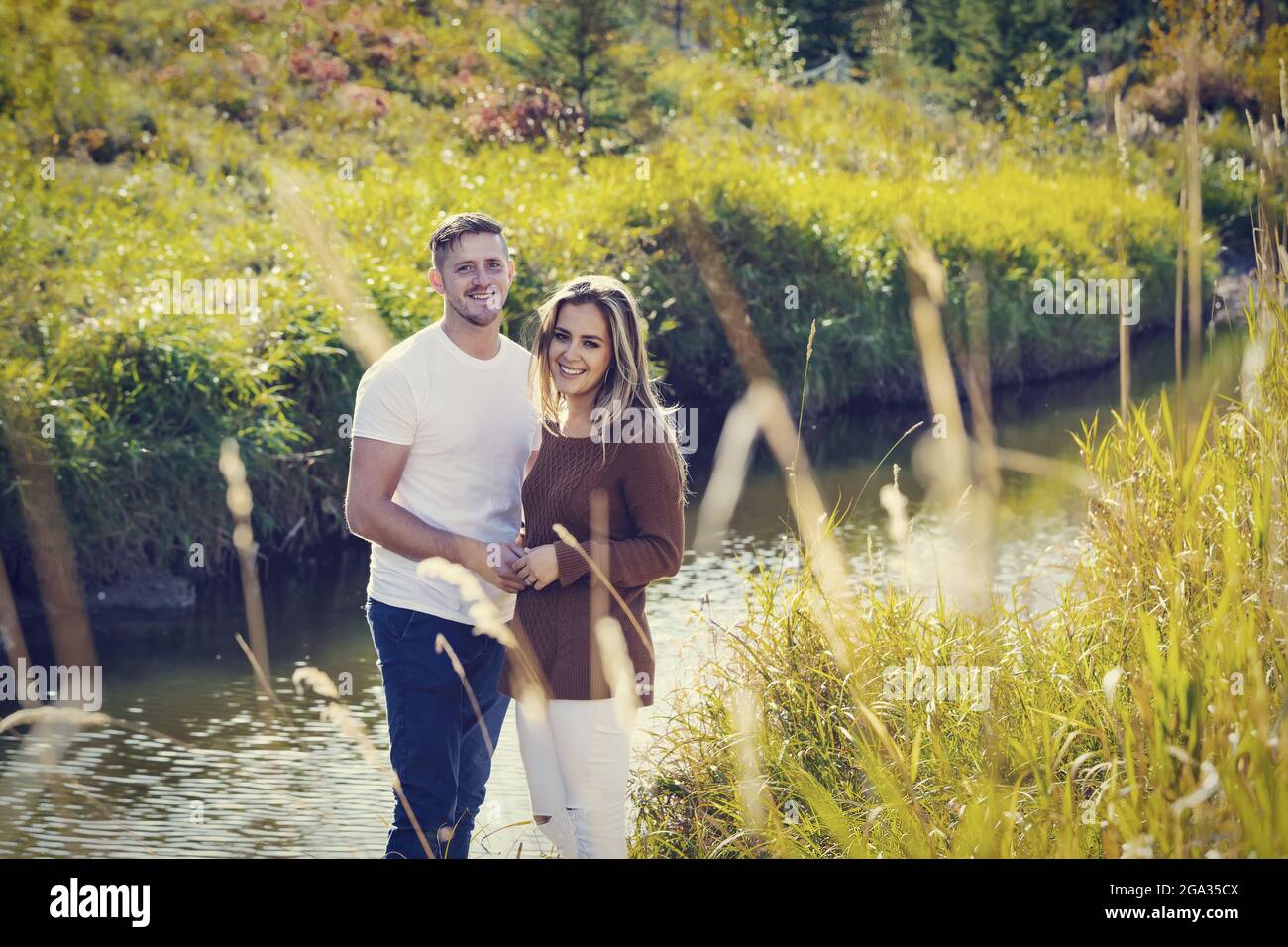 Porträt eines Mannes und einer Frau im Freien in der Nähe eines Baches in einem Stadtpark in der Herbstsaison; Edmonton, Alberta, Kanada Stockfoto