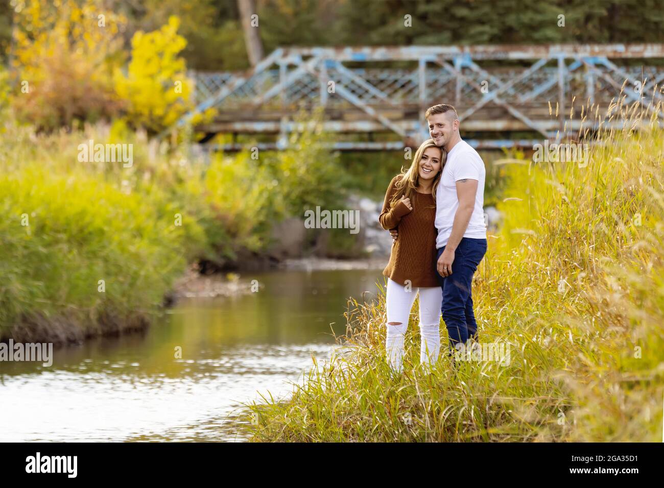 Ehemann und Ehefrau verbringen gemeinsam eine gute Zeit im Freien in der Nähe eines Baches in einem Stadtpark; Edmonton, Alberta, Kanada Stockfoto