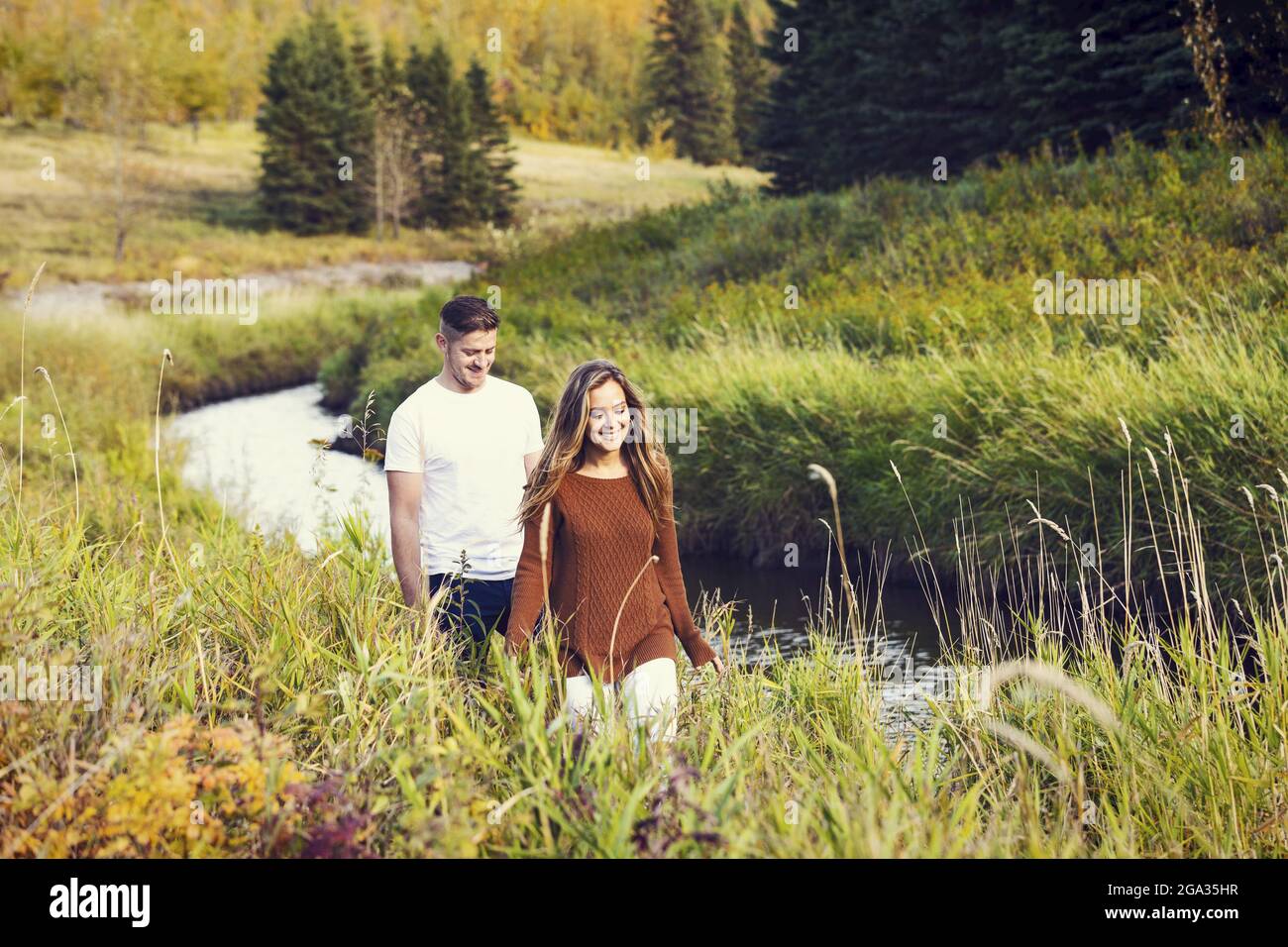 Ehemann und Ehefrau verbringen gemeinsam eine gute Zeit im Freien in der Nähe eines Baches in einem Stadtpark; Edmonton, Alberta, Kanada Stockfoto