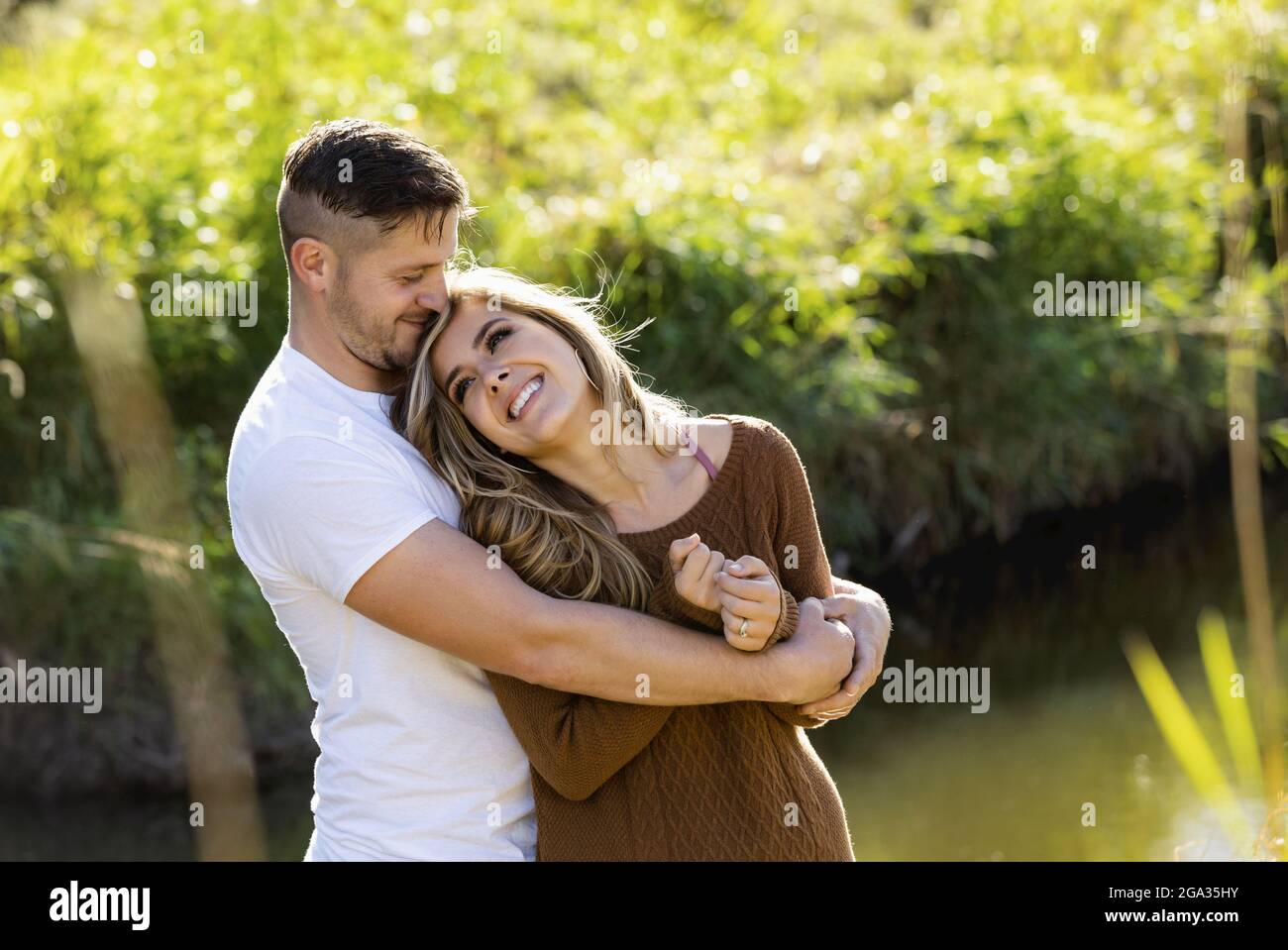 Ehemann und Ehefrau verbringen gemeinsam eine gute Zeit im Freien in der Nähe eines Baches in einem Stadtpark; Edmonton, Alberta, Kanada Stockfoto