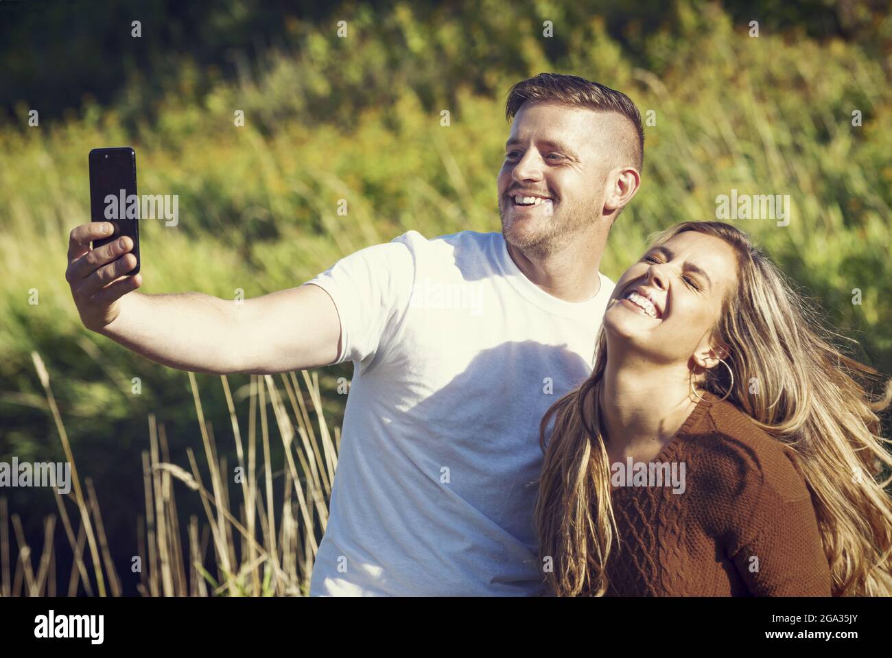 Ehemann und Ehefrau verbringen viel Zeit zusammen im Freien und machen ein Selbstporträt in einem Stadtpark; Edmonton, Alberta, Kanada Stockfoto