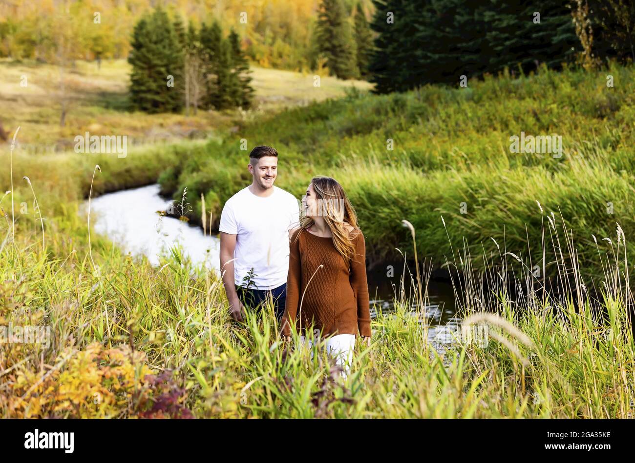 Ehemann und Ehefrau verbringen gemeinsam eine gute Zeit im Freien in der Nähe eines Baches in einem Stadtpark; Edmonton, Alberta, Kanada Stockfoto
