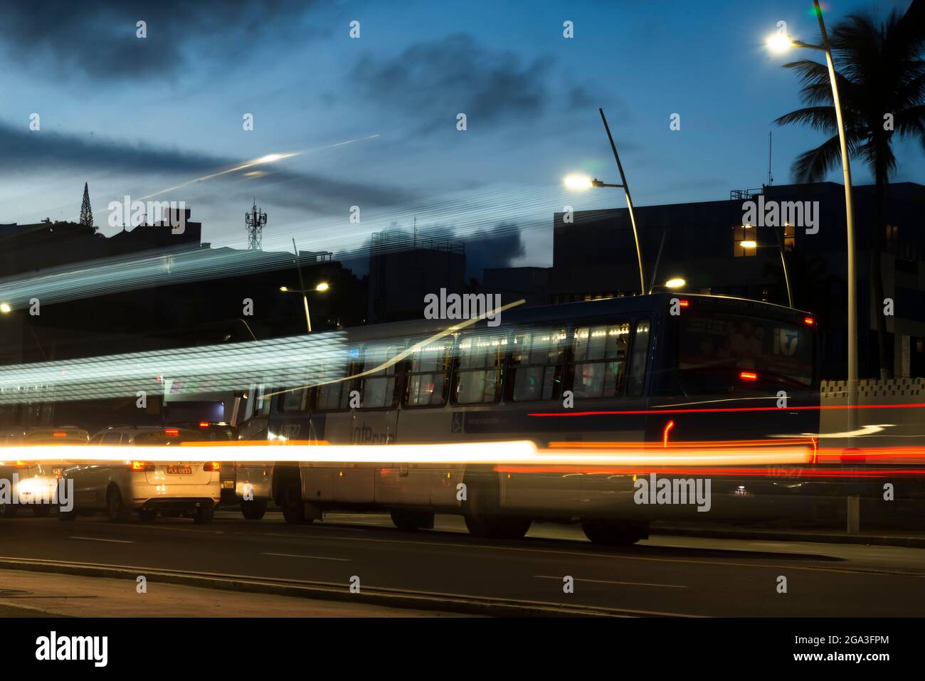 Nächtlicher Stadtverkehr mit vorbeifahrenden Autos und Bussen. Fotoeffekt bei geringer Geschwindigkeit, Lichteinfall. Stockfoto