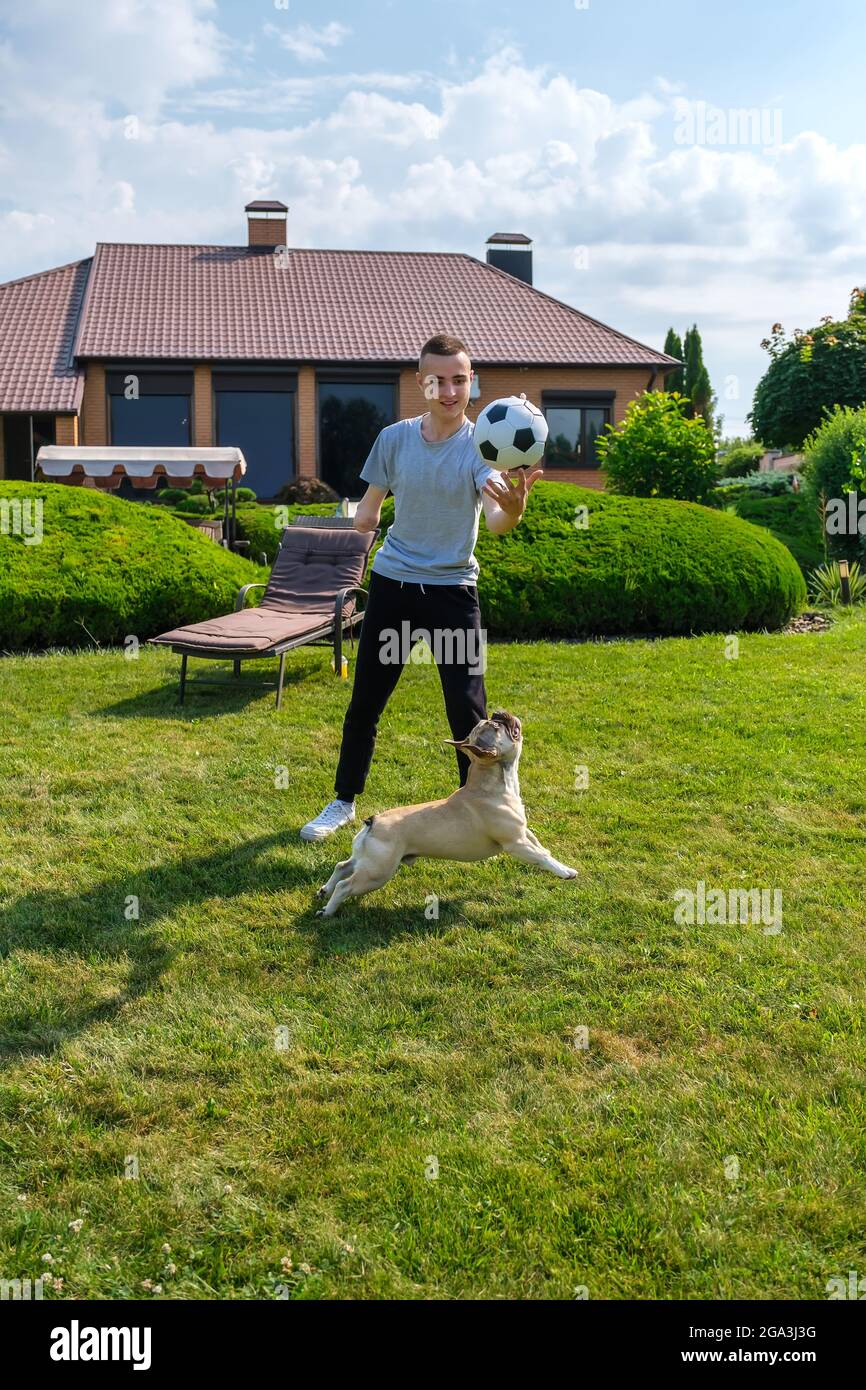 Mann mit ampuiertem Arm und Prothese, der im Hinterhof mit seinem Hund spielt Stockfoto