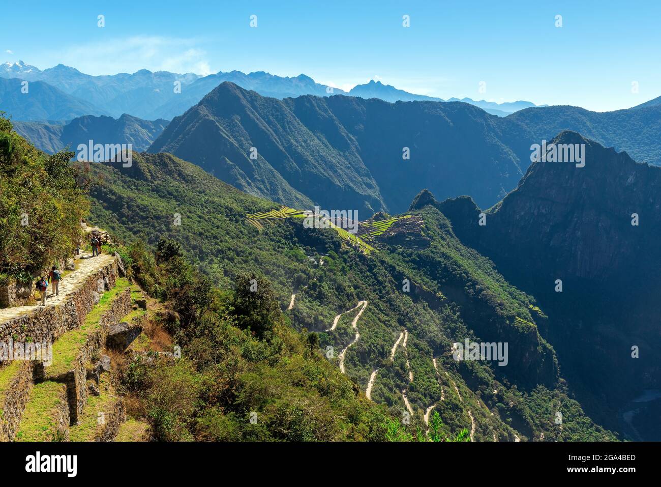 Machu Picchu inka-Ruinenlandschaft vom Sonnentor aus gesehen, mit Touristen, die den letzten Teil der Inka Trail Wanderung, Cusco, Peru, machen. Stockfoto