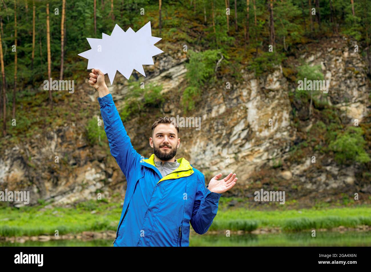 Taille von jungen bärtigen Mann mit leeren Sprechblase auf dem Hintergrund der natürlichen Landschaft. Achten Sie auf, Weg nach oben, schauen Sie nach oben Stockfoto