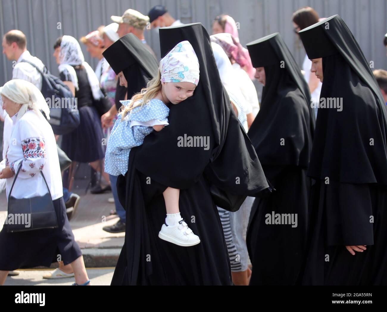 Nicht exklusiv: KIEW, UKRAINE - 27. JULI 2021 - EINE Nonne trägt ein Mädchen während der Kreuzprozession vom Wolodymyrska-Hügel (St. Wolodymyr-Hügel) zum Ky Stockfoto