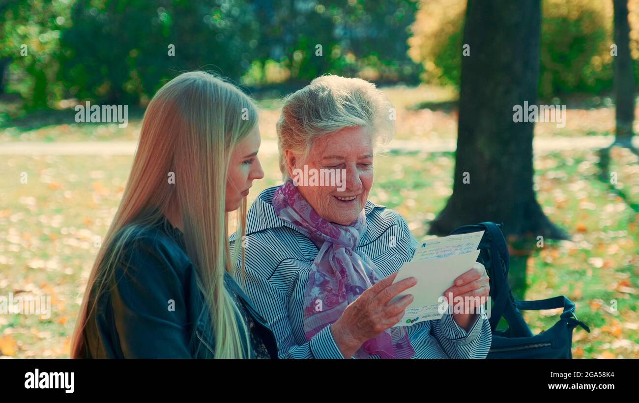 Nahaufnahme der alten Frau, die einen Brief an die hübsche junge Frau im Park liest. Sie las eine interessante Geschichte ihres Lebens. Stockfoto