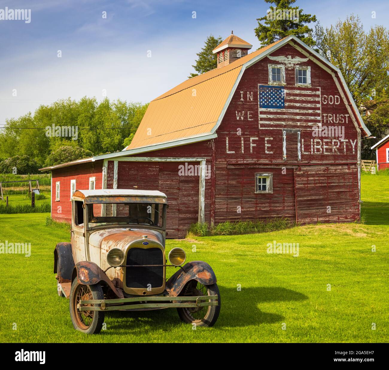 Altes Auto vor der Scheune „in god we Trust“ in Latah, einer Stadt im Spokane County, Washington, USA Stockfoto