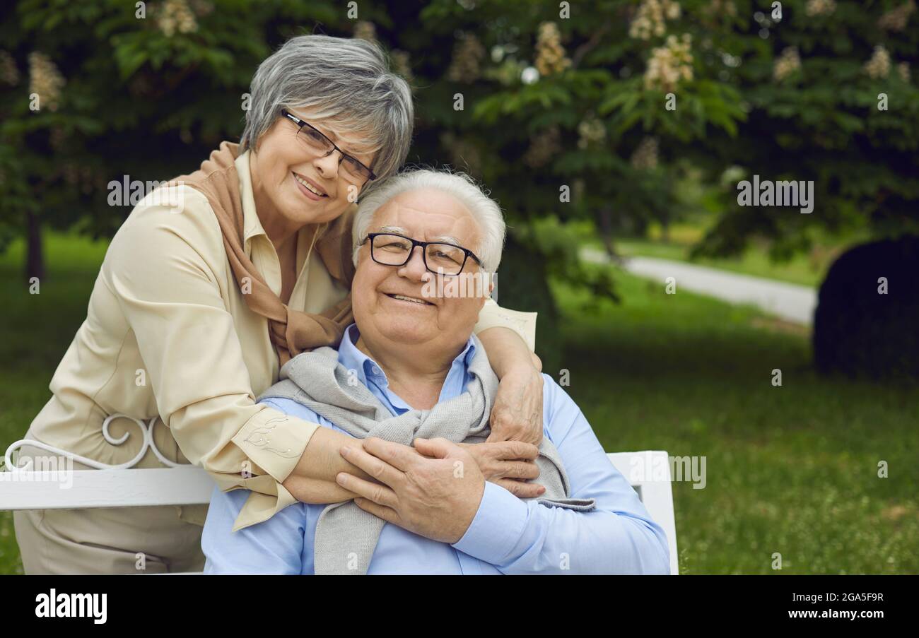 Porträt eines glücklichen älteren Paares, das lächelt und die Kamera im grünen Sommerpark anschaut Stockfoto