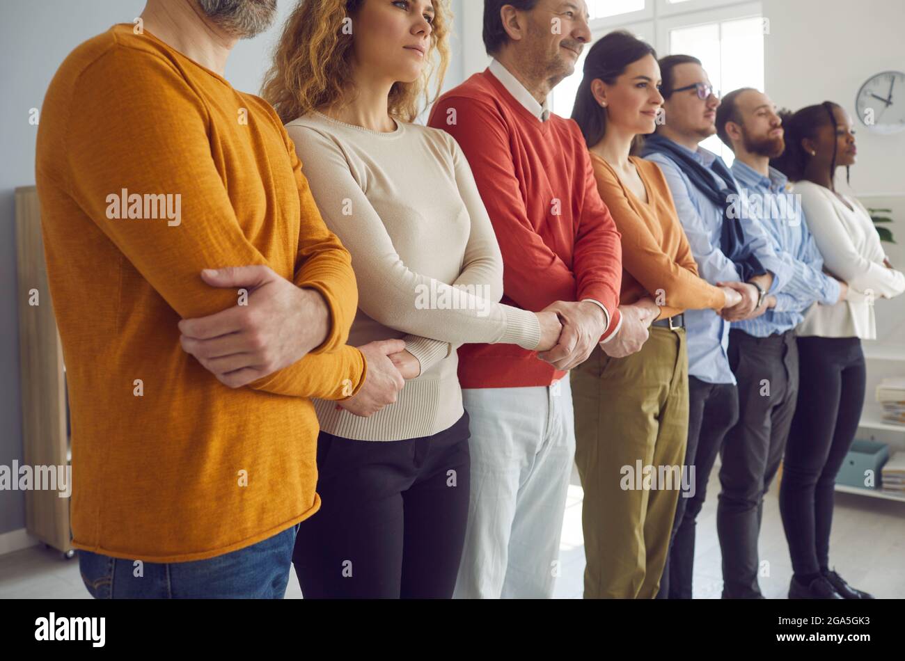 Gruppe von verschiedenen Menschen, die in Reihe stehen und die Hände halten, als Konzept der Unterstützung durch die Gemeinschaft Stockfoto