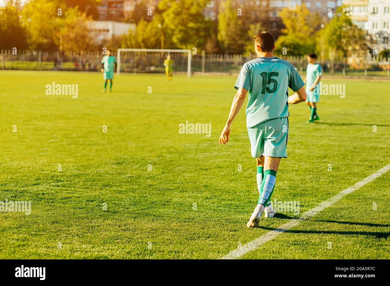 Professioneller Fußballspieler oder Fußballspieler in Aktion im Stadion, den Ball schlagen, um das Tor zu erreichen, junger sportlicher männlicher Fußballspieler auf dem Sockel Stockfoto