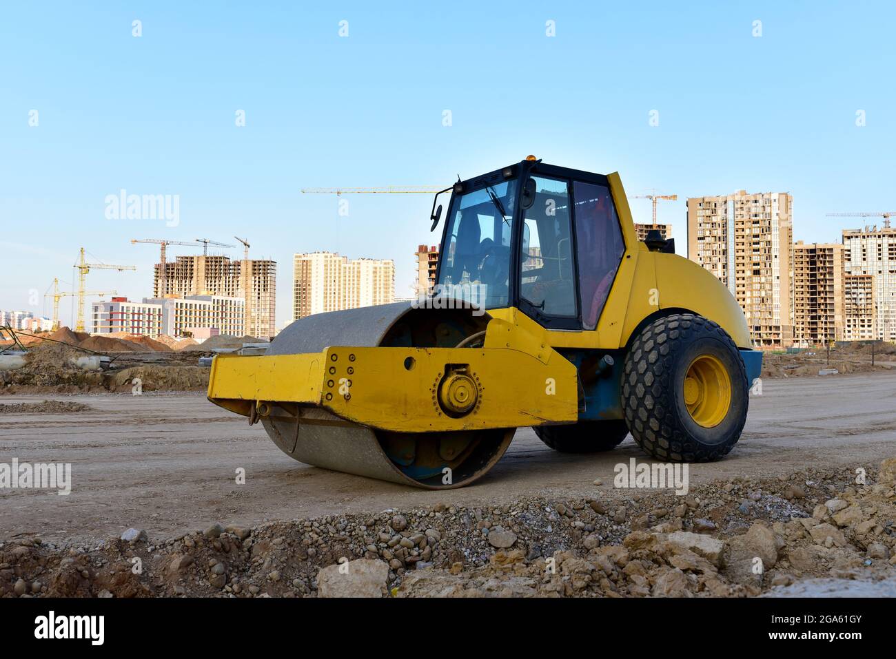 Vibration Einzylinder-Straßenwalze Nivellierboden für den Bau der neuen  Asphaltstraße. Straßenarbeiten und Straßen reparieren.Turmkrane in Aktion  bei c Stockfotografie - Alamy