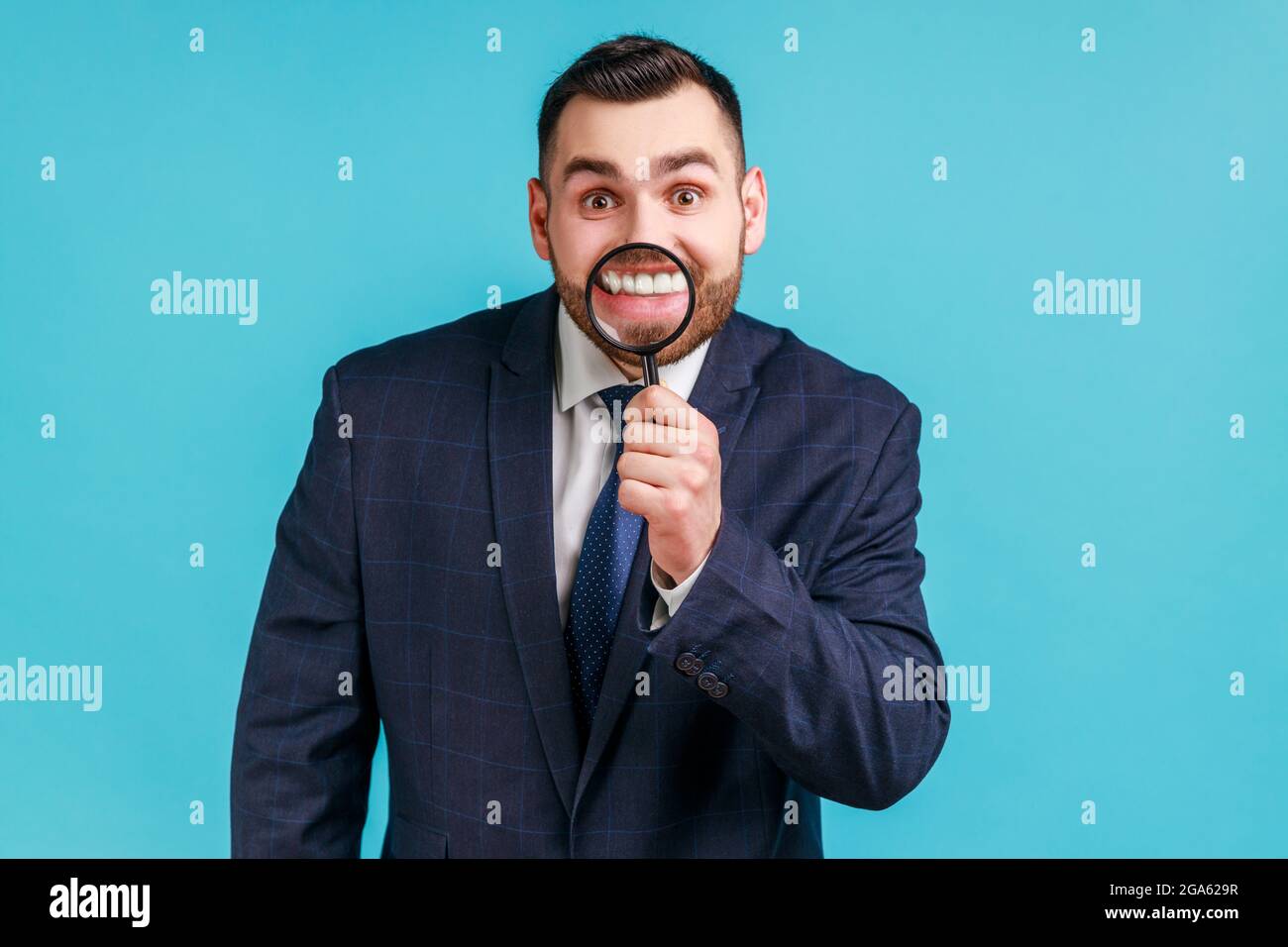 Lächeln-Zoom oder Zahnpflege-Konzept. Porträt eines jungen Geschäftsmannes im Anzug stehend, mit Lupe auf den Zähnen, mit einem toothy Lächeln. Zoll Stockfoto