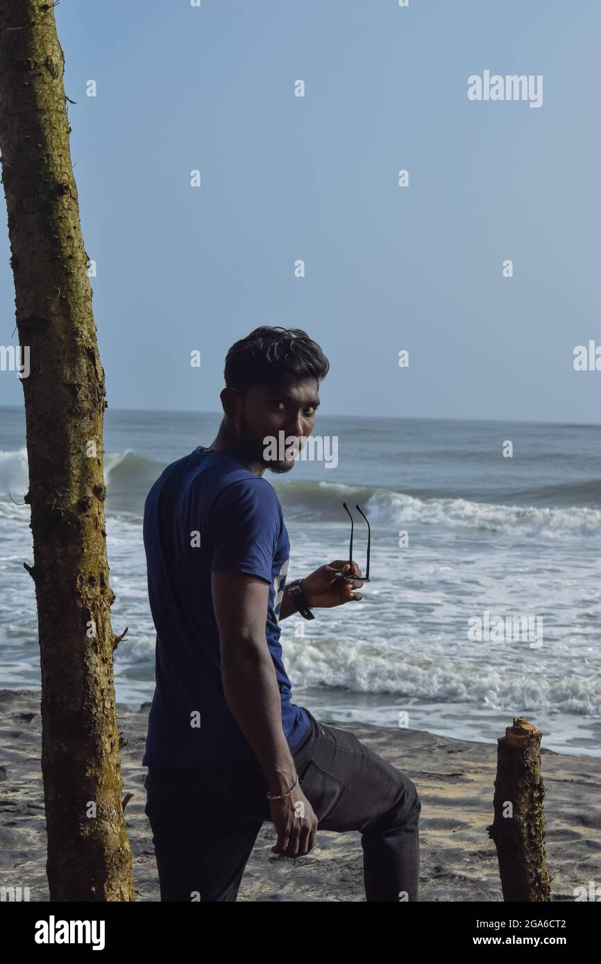 Junger Mann, der am Strand steht und auf das Meer schaut. Stockfoto