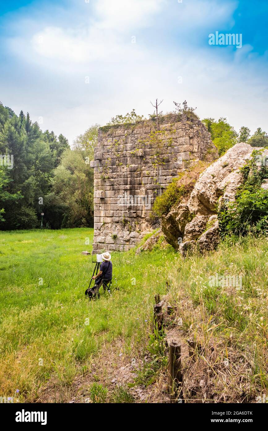 Ein Künstler malt die Ruinen der römischen Bogenbrücke des Augustus in Narni, Terni, Umbrien. Plein Luftmalerei, Impressionismus. Die Überreste des b Stockfoto