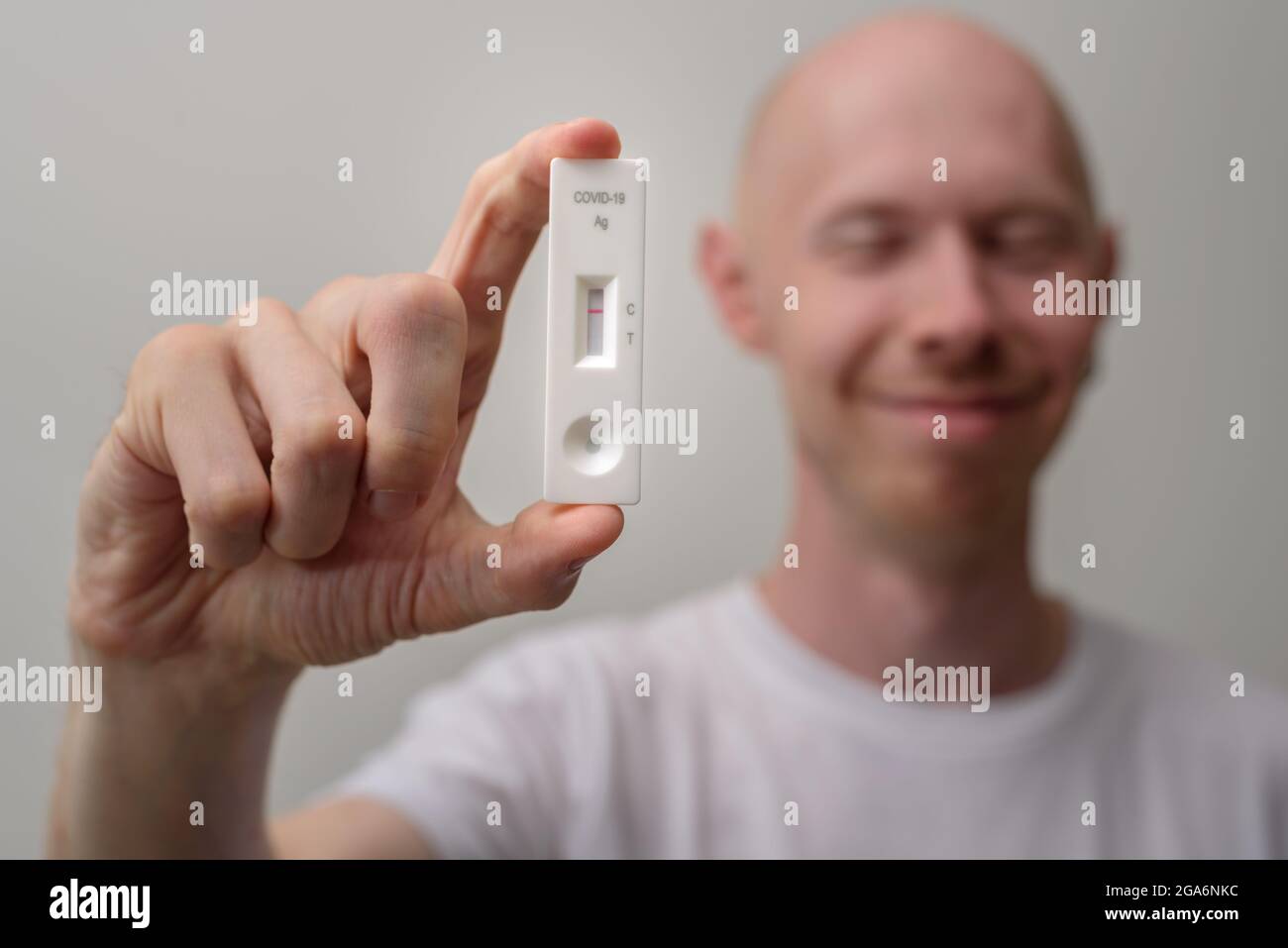 Glücklicher Mann mit negativem Antigenkovidtest in der Hand Stockfoto