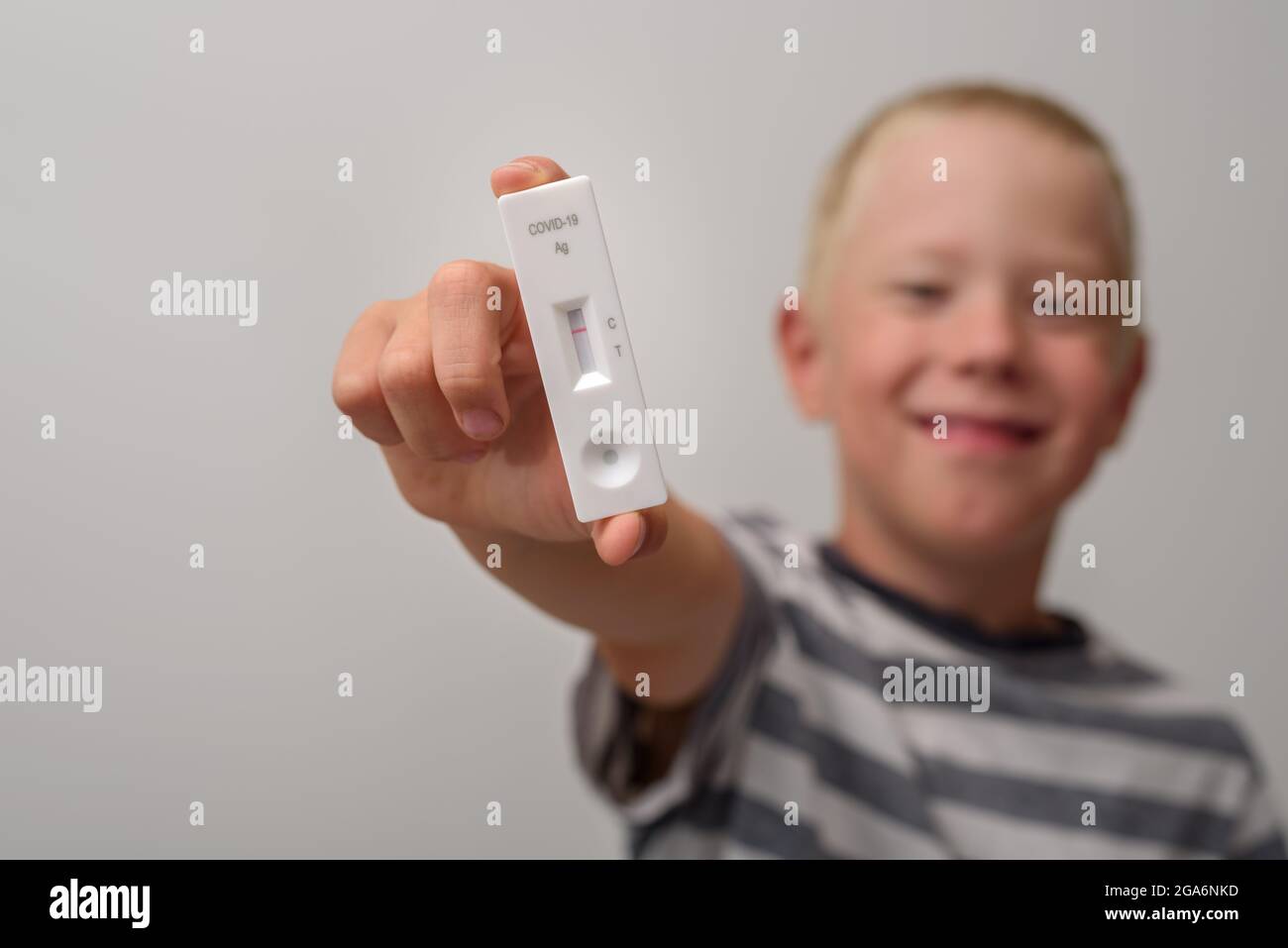 Happy Boy Kind mit negativem Antigen-Covid-Test in der Hand Stockfoto