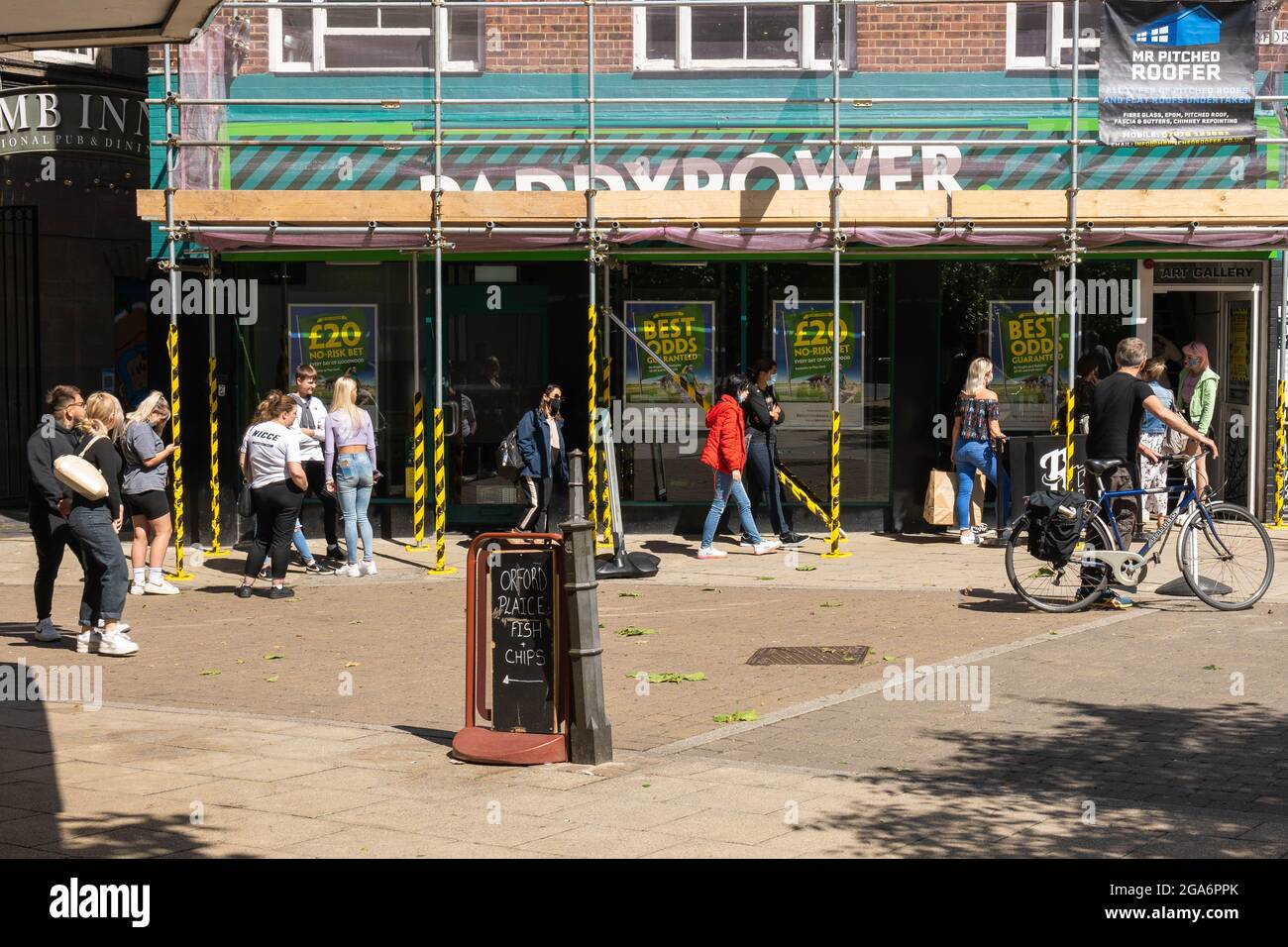 Orford Place Norwich City Centre Paddy Power Buchmacher mit Rudeboy Studios und einem Tattoo- und Piercing-Shop mit Menschen, die draußen für Piercings Schlange stehen. Stockfoto