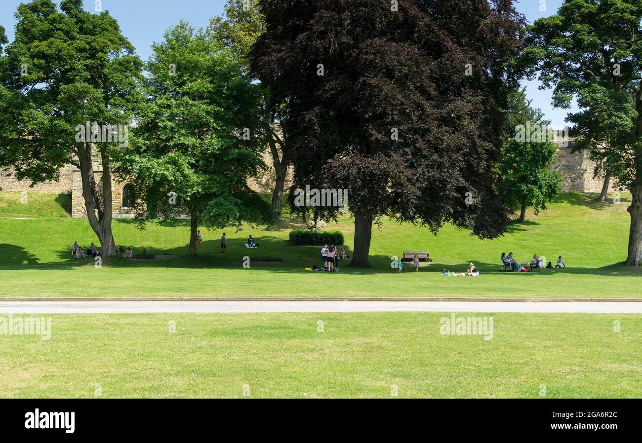 Leute, die im Schatten der Bäume unter heißer Sonne auf dem Schlossgelände picknicken Lincoln Lincolnshire 2021 Stockfoto
