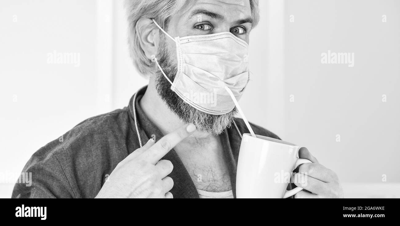 Hygiene ist ernst. Kerl in Maske trinken Tee Kaffee mit Stroh. Mund und Nase mit Maske abdecken und sicherstellen, dass keine Lücken zwischen Gesicht und Maske bestehen. Absolut Stockfoto