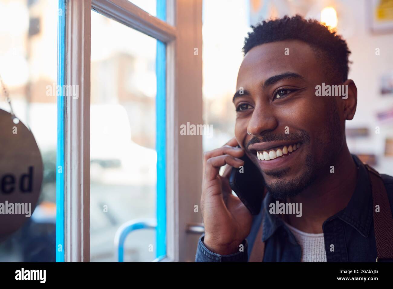 Inhaber Eines Kleinen Unternehmens, Der Am Geschäftstor Steht Und Auf Dem Mobiltelefon Anruft Stockfoto