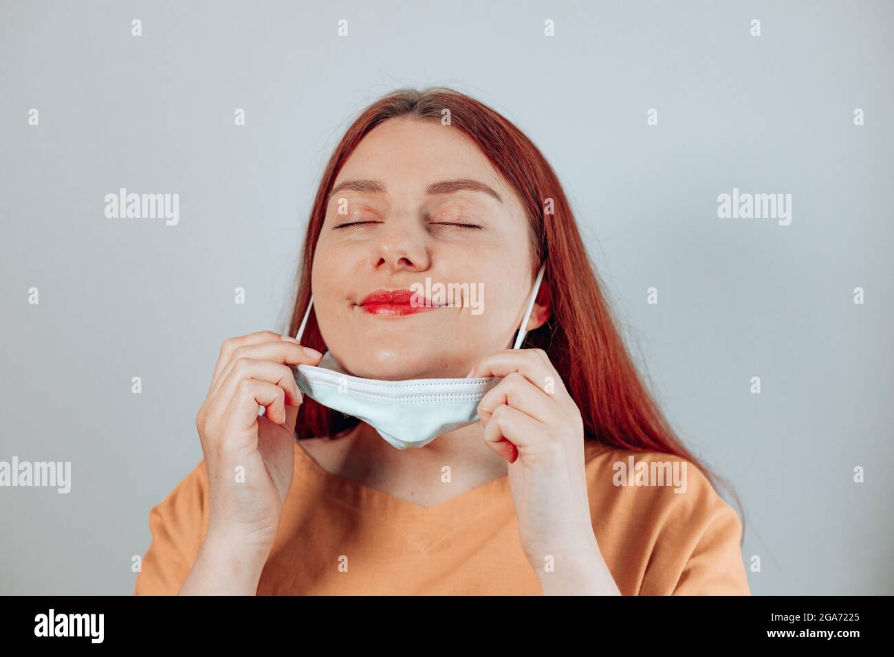Kaukasische Frau, die schützende medizinische Maske abnimmt. Wir haben gewonnen. Keine Quarantäne mehr. Stockfoto