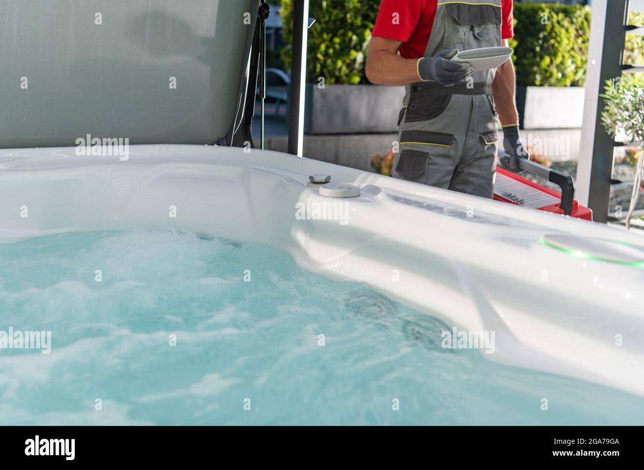 Kaukasischer Whirlpool-Techniker, der Wohngarten SPA-Service durchführt. Stockfoto