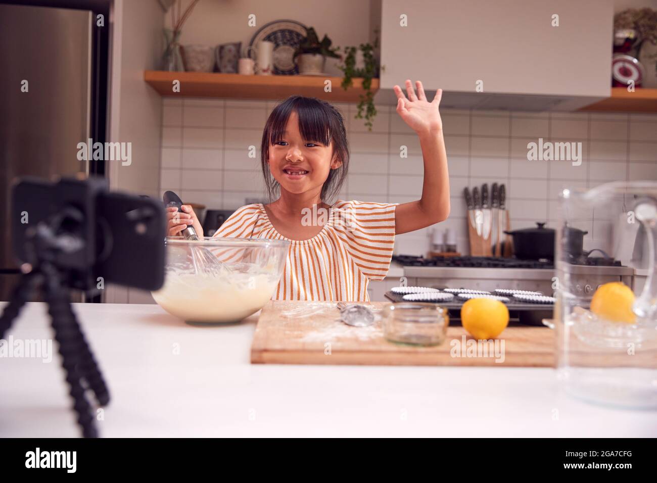 Asiatische Mädchen Backen Cupcakes In Der Küche Zu Hause, Während Auf Vlogging Auf Handy Stockfoto