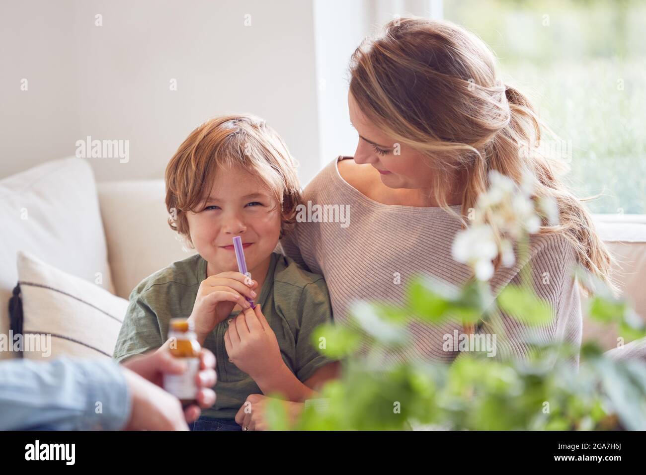 Eltern Geben Sohn Medizin Mit Spritze Sitzen Auf Sofa Zu Hause Stockfoto
