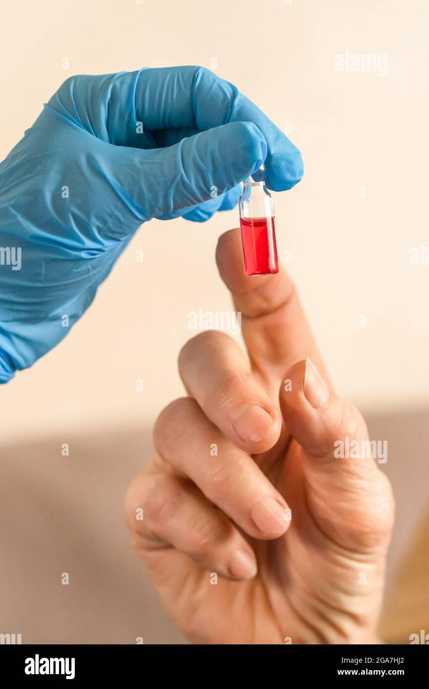 Die Hand einer Krankenschwester reicht einer älteren Frau eine Ampulle Medizin aus Stockfoto