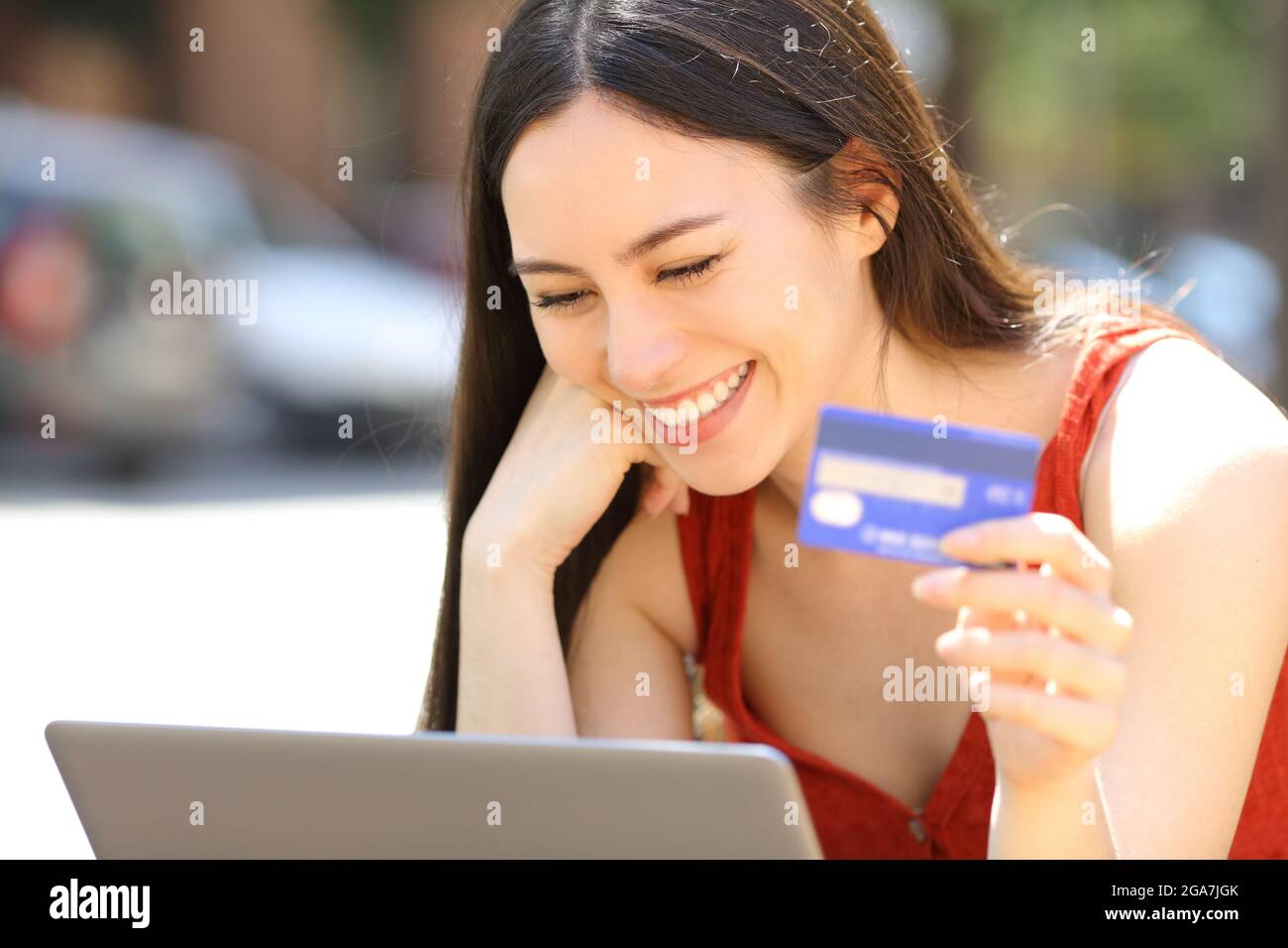 Asiatische Frau, die online mit Kreditkarte und Laptop auf der Straße kauft Stockfoto