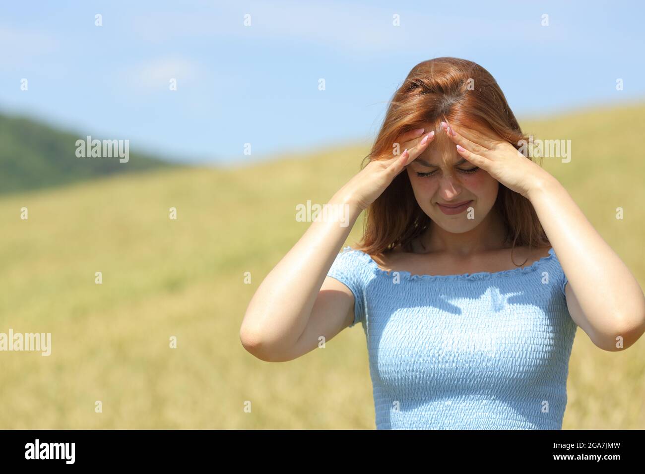 Vorderansicht Porträt einer Frau, die in einem Weizenfeld an Migräne leidet Stockfoto