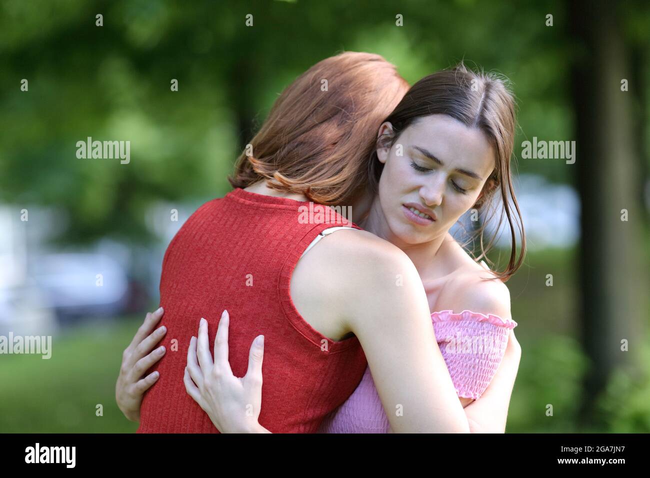 Heuchlerische Frau trifft sich und umarmt ihre Freundin in einem Park Stockfoto