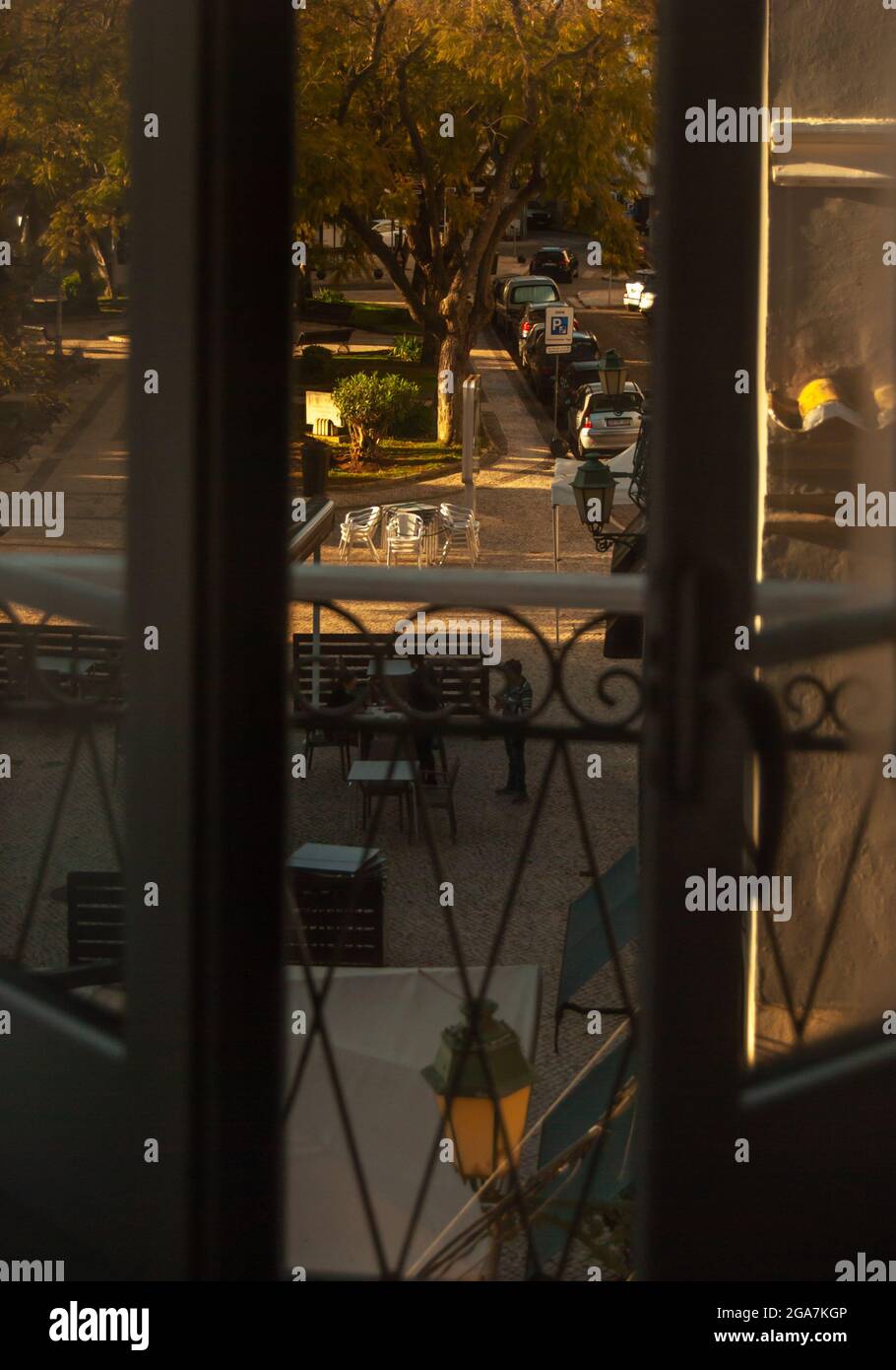 Durch das geöffnete Fenster ein Stadtplatz im frühen Morgensonnenlicht Stockfoto
