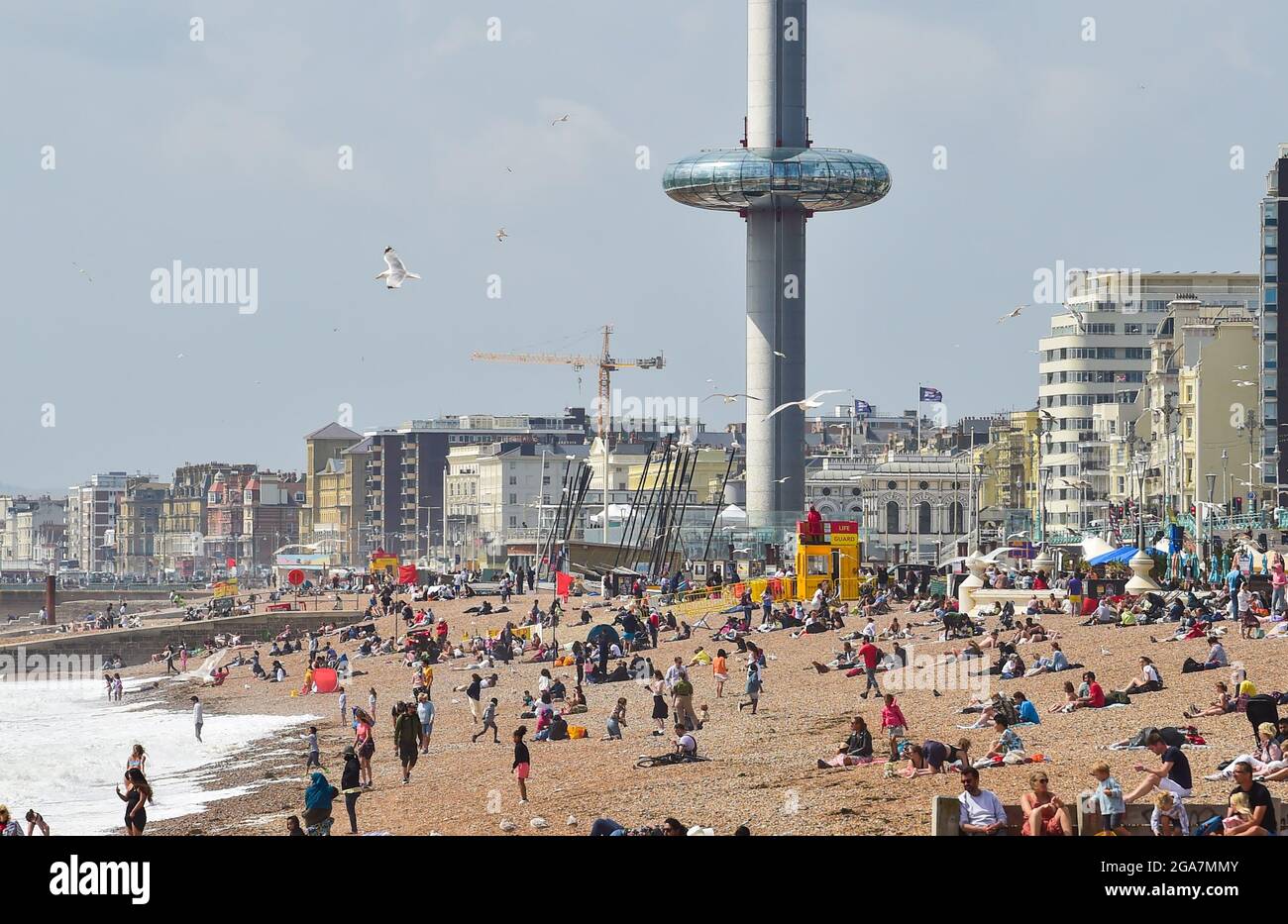 Brighton UK 29. Juli 2021 - der Aussichtsturm i360 erhebt sich über die Besucher und genießt einen sonnigen, aber luftigen Tag am Strand von Brighton. Die unruhigen Wetterprognosen werden in den nächsten Tagen in Großbritannien fortgesetzt. : Credit Simon Dack / Alamy Live News Stockfoto